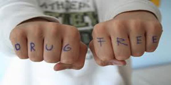 Hands with 'DRUG FREE' written across the knuckles